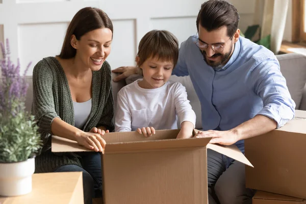 Feliz niño pequeño unboxing pertenencias familiares con los padres . — Foto de Stock