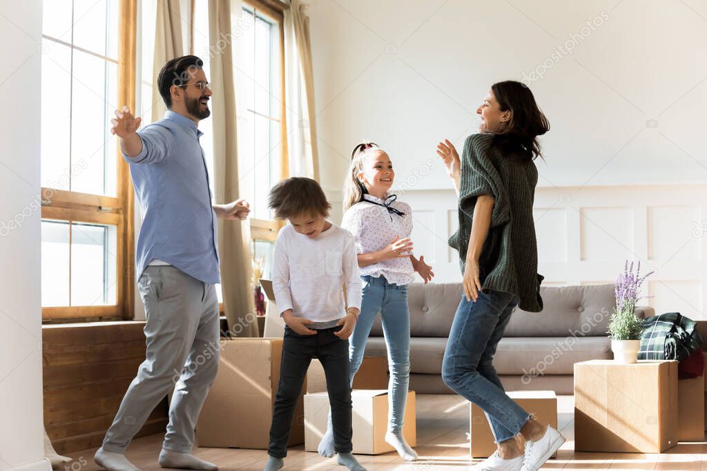 Overjoyed young parents dancing to energetic music with small kids.