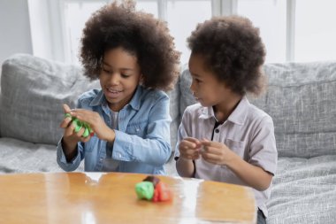 African siblings using playdough have fun making diverse shapes clipart