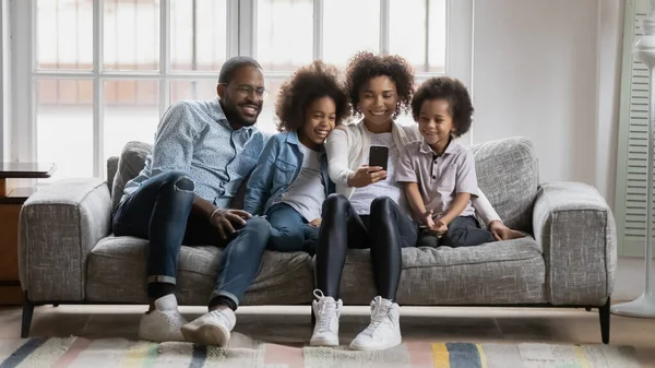 Happy African family with small children making selfie using smartphone