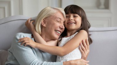 Neşeli yetişkin büyükanne evde küçük torunuyla oynuyor.