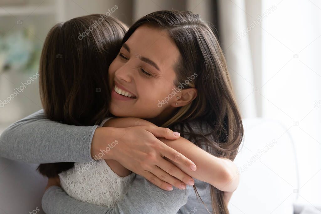 Smiling young mother and little daughter hug making peace