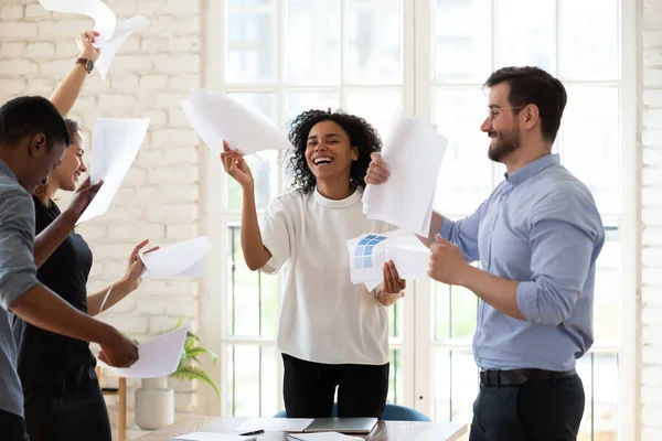 Multiracial staff members dancing throwing papers feels overjoyed ending workday — Stock Photo, Image