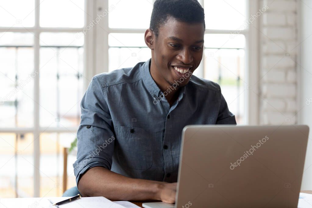 African office employee sitting at workplace typing on laptop