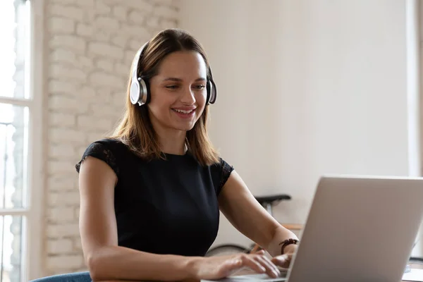 Woman wearing headphones working typing on notebook enjoy e-learning process — Stock Photo, Image