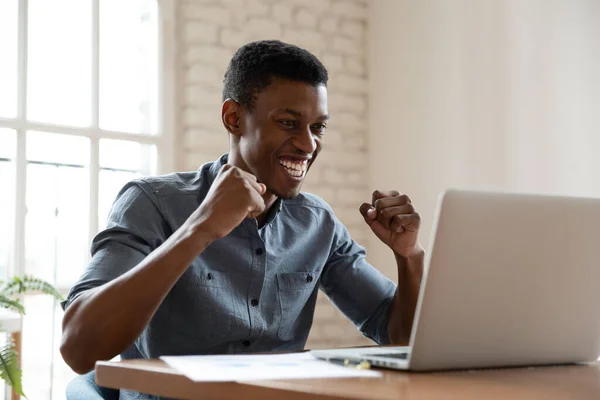 Africano empresário sentado na mesa se sente animado ler grandes notícias — Fotografia de Stock