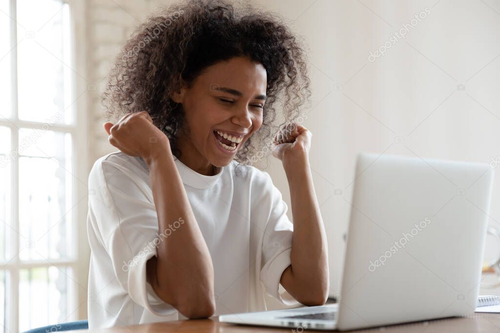 African woman sit at desk feels overjoyed read great news