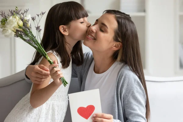 Lilla dotter gratulera glada unga mamma presentera blommor — Stockfoto