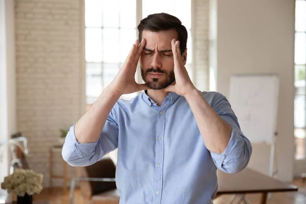 Empresario toca la cabeza ojos cerrados se siente enfermo sufre de dolor de cabeza —  Fotos de Stock