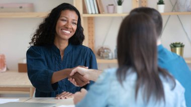 Çift ırklı kadın ajan müşterilerle tokalaşıyor.