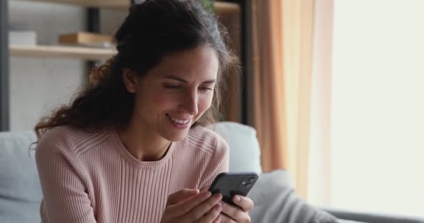 Mujer milenaria sonriente viendo historias de video en un teléfono inteligente — Vídeos de Stock