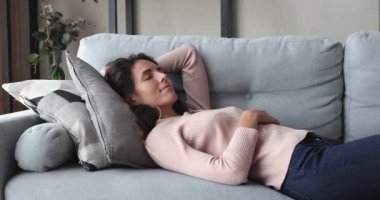 Rahatlamış genç bir kadın evdeki rahat kanepede kestiriyor.