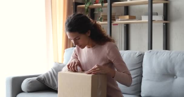 Glad ung kvinna packa upp leverans paket låda hemma — Stockvideo