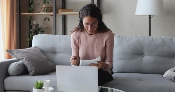 Mujer joven con auriculares conferencia de llamadas en el ordenador portátil en casa — Vídeo de stock
