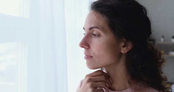 Pensive bezorgd jonge volwassen vrouw kijken buiten door het raam — Stockvideo