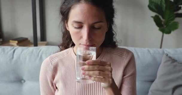 Жаждущая молодая женщина держит стакан питьевой воды, чтобы оставаться здоровым — стоковое видео