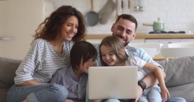 Mutlu ebeveynler ve çocuklar evde eğlenirken dizüstü bilgisayar kullanıyorlar.