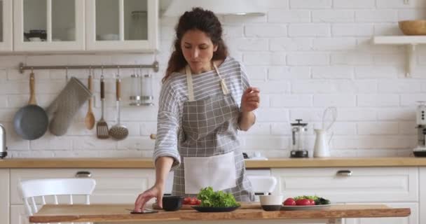 Felice giovane donna che prepara insalata di verdure utilizzando l'app di ricettario mobile — Video Stock