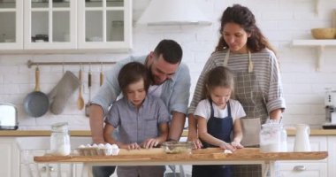 Mutlu ebeveynler ve çocuklar hamuru merdaneyle birlikte hazırlıyorlar.