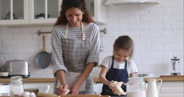 Счастливая мама учит ребенка дочь месить тесто на кухне вместе — стоковое видео