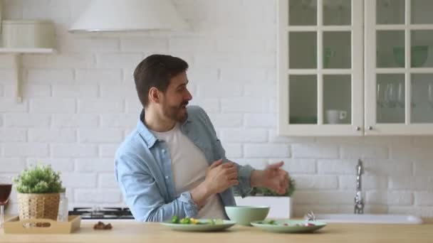 Aktiv tusenårig man som har roligt i modernt kök. — Stockvideo