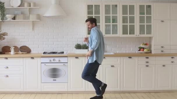 Full length overjoyed young funky guy funny dancing in kitchen. — Stock Video