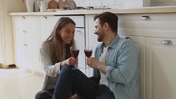 Gelukkig getrouwde echtgenoot toasten glazen wijn, zitten op de vloer. — Stockvideo