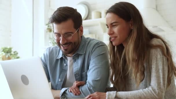 Lächelndes Mischlingspaar nutzt Computer zu Hause. — Stockvideo