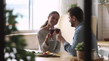 Genç evli eş kırmızı şarapla kadeh tokuşturuyor..