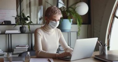 Maske takan ve eldiven takan iş kadını laptopta çalışıyor.