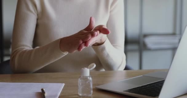 Молодая женщина применяет дезинфицирующее средство трения рук перед дистанционной компьютерной работой — стоковое видео