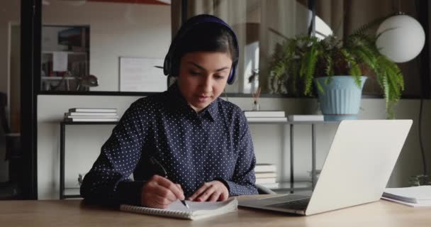 Female indian distance worker wearing headphones video calling making notes — Stock Video