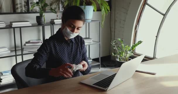 Mujer de negocios india lleva máscara facial desinfectando teclado portátil con desinfectante — Vídeos de Stock