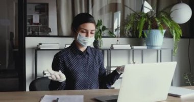 Yüz maskesi takan Hintli iş kadını laptoptaki video çağrısı ile iletişim kuruyor.