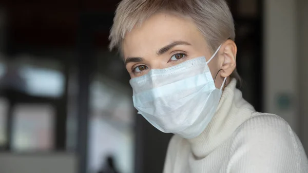 Responsible blonde woman in facial mask looking at camera. — Stock Photo, Image