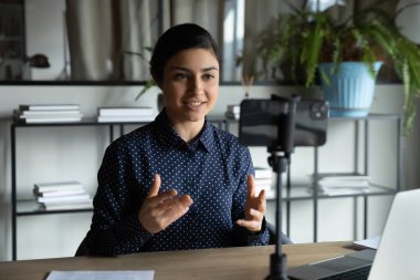 Gülümseyen Hintli kız akıllı telefonun önünde dengeleyicinin üzerinde oturuyor..