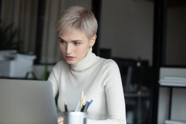 Ofiste dizüstü bilgisayarla çalışan başarılı konsantre bir çalışan..