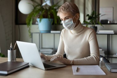 Tıbbi maske ve eldivenlerle çalışan konsantre genç bayan çalışanlar..