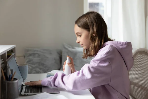 Young female teenager treating computer keyboard with antibacterial spray. — Stock Photo, Image