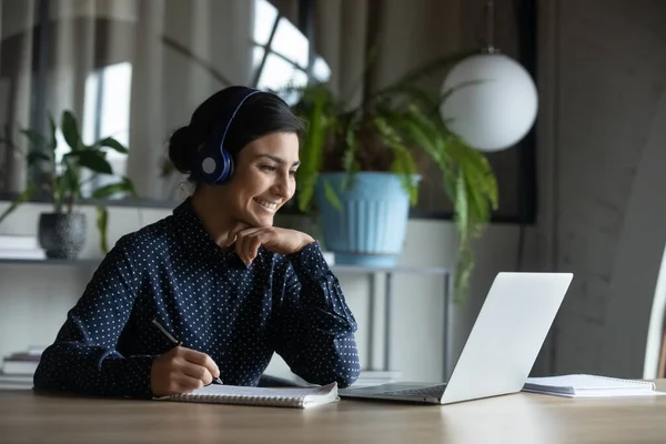 Happy young indian girl with headphones looking at laptop screen. — Stock Photo, Image