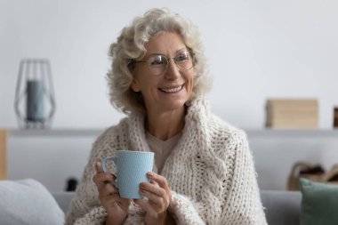 Mutlu orta yaşlı kadın kendini sıcak içecekle ısıtıyor..