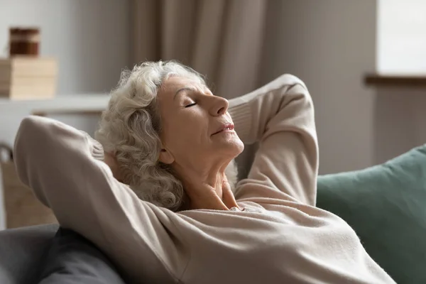 Serene middle aged woman daydreaming on couch. — Stock Photo, Image