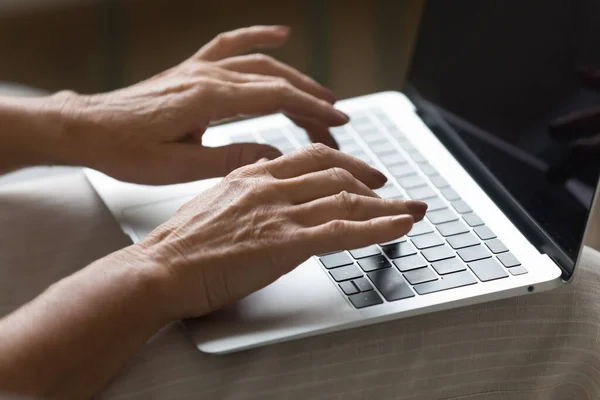 Wrinkled female hands typing message on laptop keyboard. — Stock Photo, Image