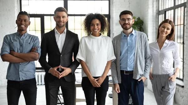 Standing in row smiling diverse team posing differently. — Stock Photo, Image