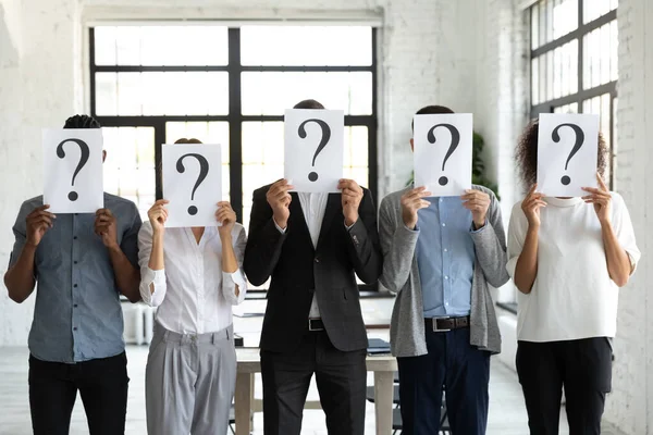 Empresários escondendo rostos atrás de folhas de papel com pontos de interrogação . — Fotografia de Stock