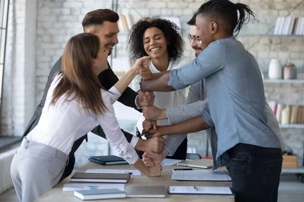 Sourire divers employés empilent les poings lors d'une réunion d'entreprise, célébrant le succès . — Photo