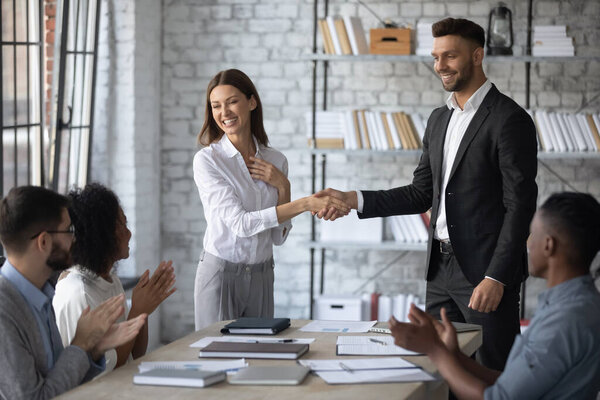 Smiling businessman shaking hand and congratulations young attractive businesswoman.