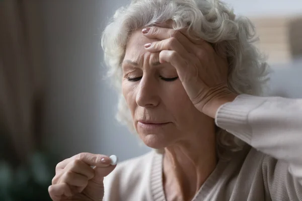 Worrying middle aged grandmother taking pills painkiller. — Stock Photo, Image