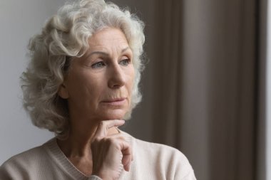 Düşüncelere dalmış, orta yaşlı kadın dışarı bakıyor..