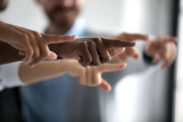 Diverse business team hands showing pointing fingers to main goal.